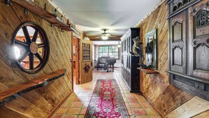 A wooden interior with a large wooden wheel, a piano, and a red patterned rug. - Sandy Shore & Multi-boat Dock! St Johns River Home (Astor)