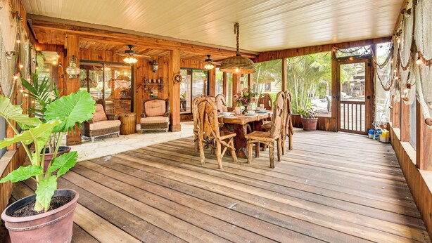 A wooden deck with a dining area, potted plants, and a view of the outdoors. - Sandy Shore & Multi-boat Dock! St Johns River Home (Astor)