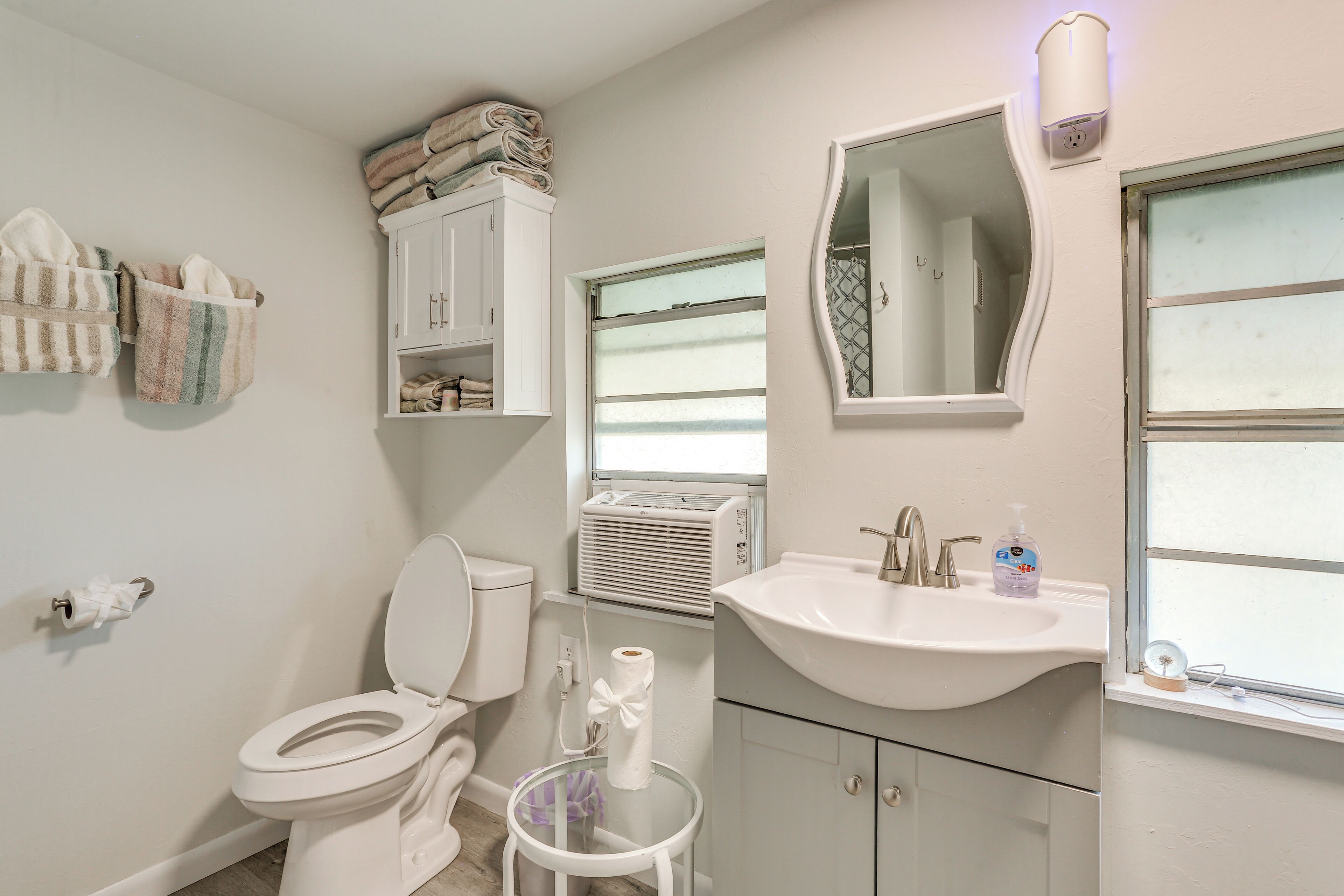 A bathroom with a toilet, a sink, a mirror, and a towel rack.