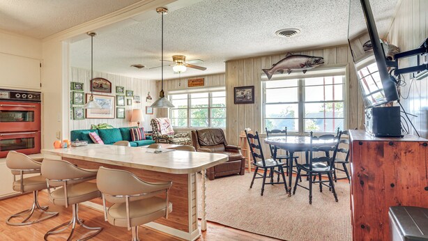 Una cocina amplia con una isla central, un comedor con mesa y sillas de madera, y una sala de estar con sofá y mesa de centro.