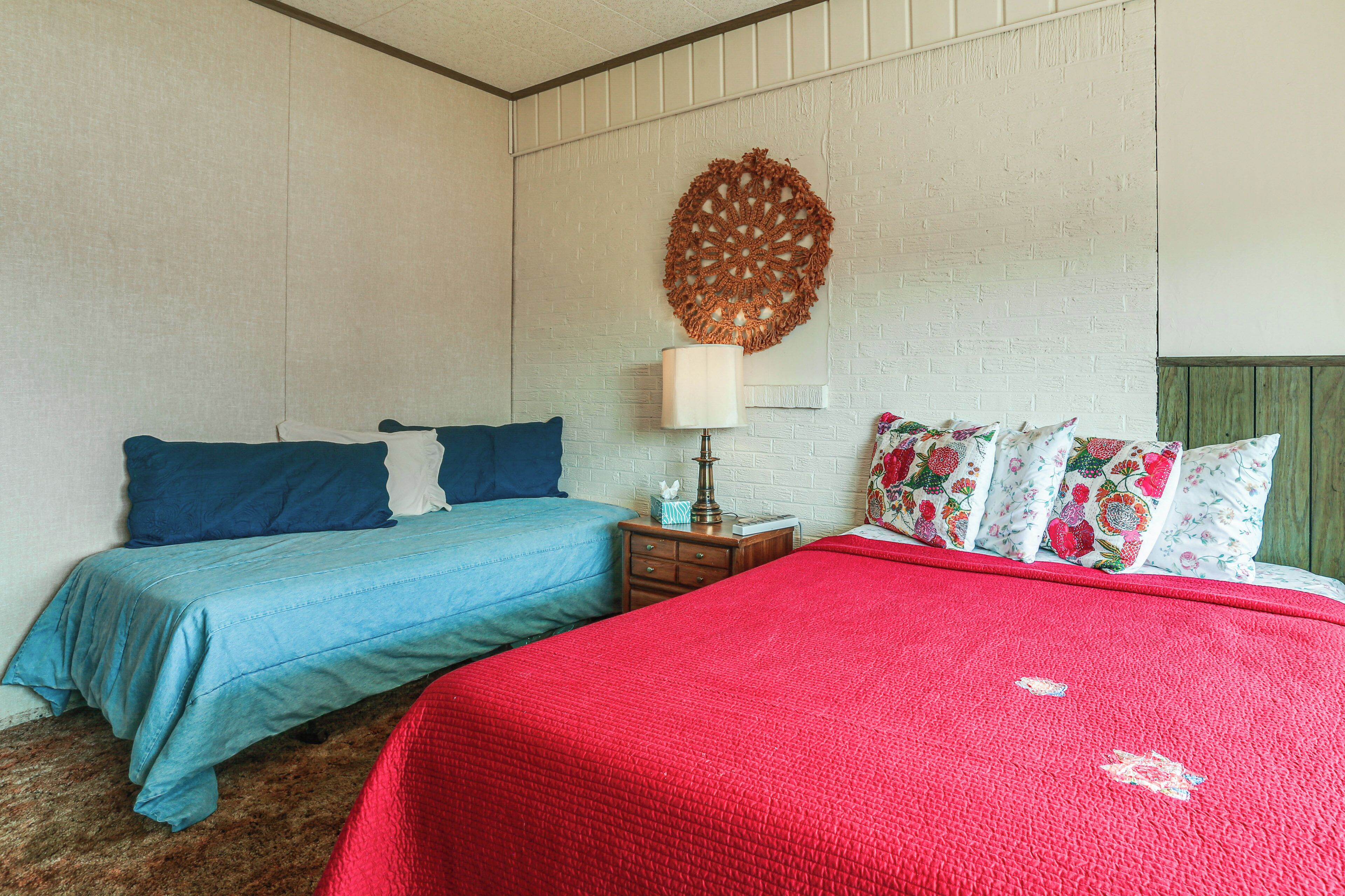 Un dormitorio con dos camas, una con colcha roja y la otra con colcha azul.