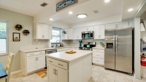 A modern kitchen with white cabinets, stainless steel appliances, and a central island. - 3 Mi to Manasota Key: Stylish Single-story Home! (Venice)