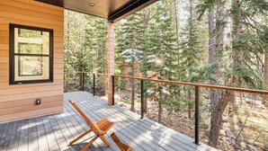 A wooden deck with two wooden chairs, a glass door, and a view of a forest. - 4 Mi to Soda Springs Resort: Hot Tub Hideaway! (Truckee)