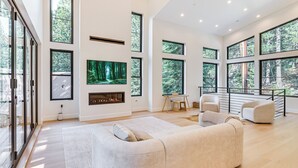 A spacious living room with a large sofa, a fireplace, and a television mounted on the wall. - 4 Mi to Soda Springs Resort: Hot Tub Hideaway! (Truckee)