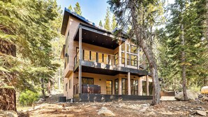 A modern two-story building with a balcony, surrounded by trees and rocky terrain. - 4 Mi to Soda Springs Resort: Hot Tub Hideaway! (Truckee)