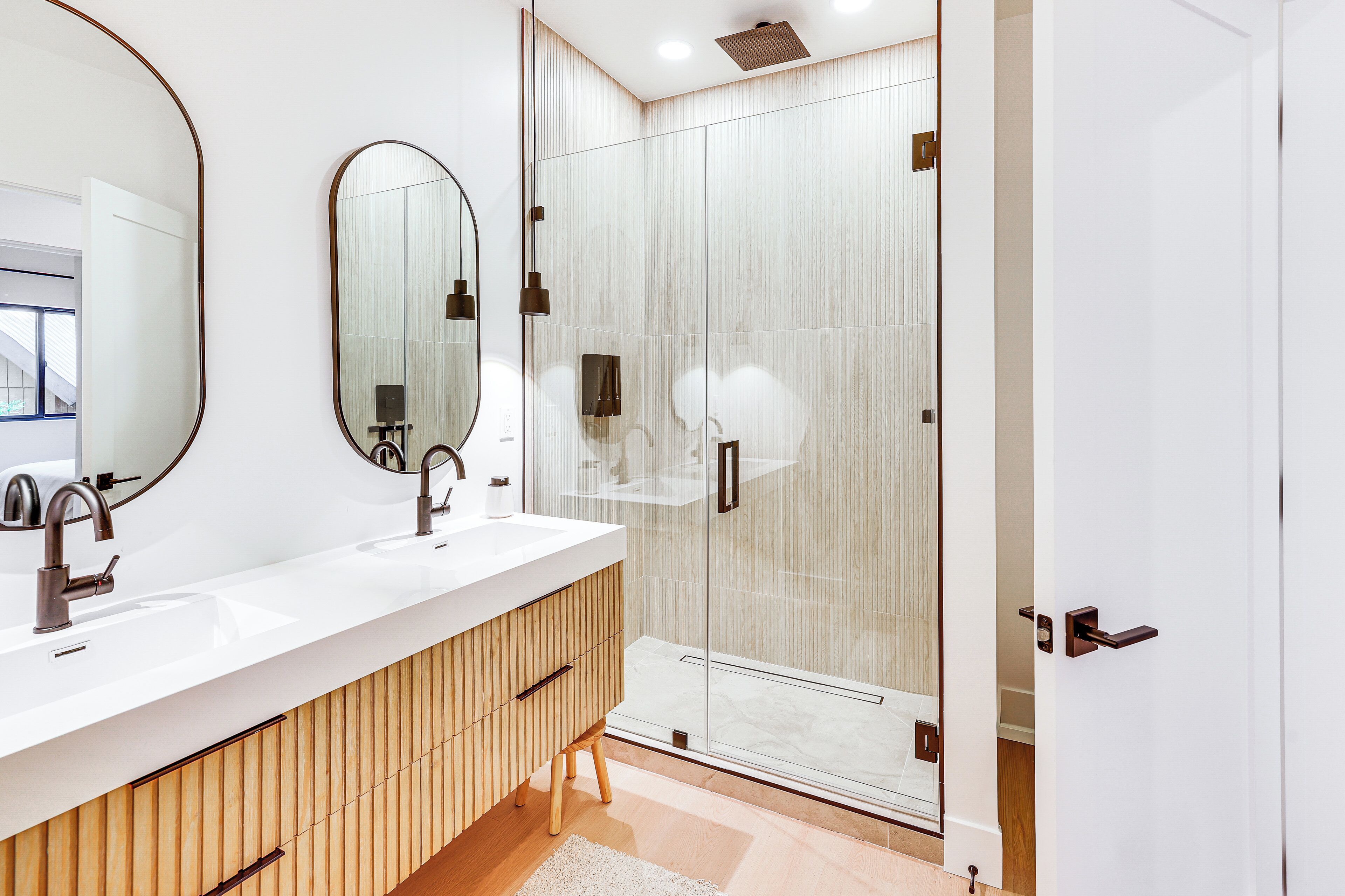 Une salle de bain moderne avec un meuble-lavabo en bois, un grand miroir et une cabine de douche en verre.