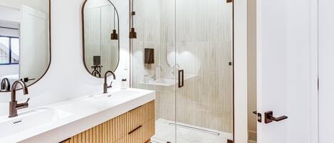 Une salle de bain moderne avec un meuble-lavabo en bois, un grand miroir et une cabine de douche en verre.