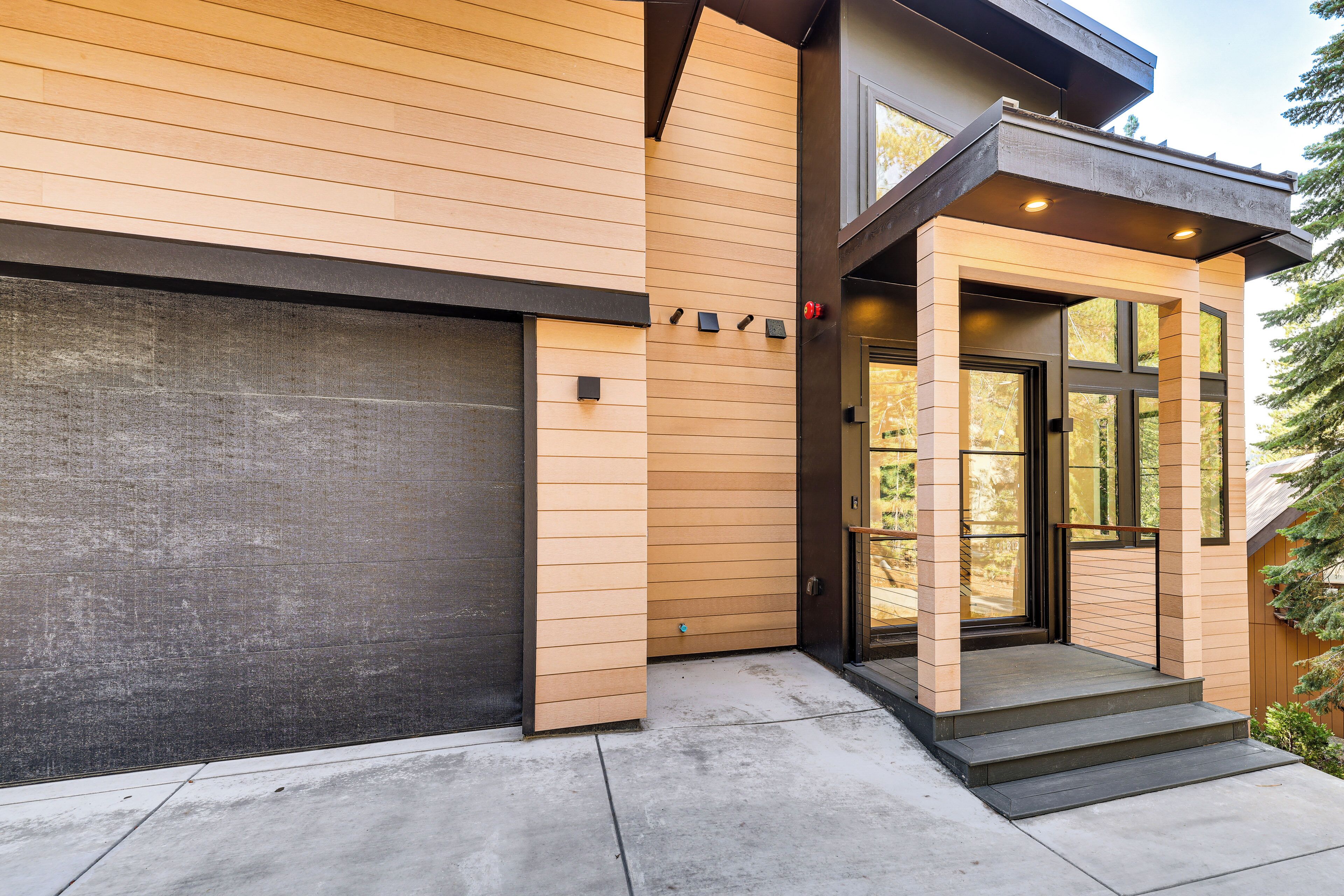 A modern house with a garage, wooden siding, and a front entrance with steps.