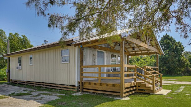 A small, single-story building with a wooden porch and a covered area. - Private Dock: Des Allemands Cabin on the Bayou! (Des Allemands)