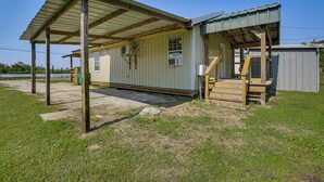 A single-story building with a covered porch and a small staircase leading to a door. - Private Dock: Des Allemands Cabin on the Bayou! (Des Allemands)