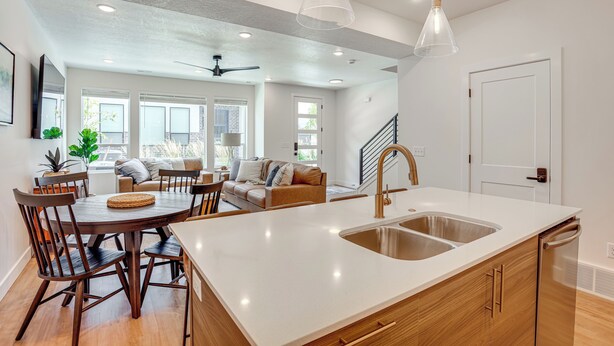 A modern kitchen with a large island, white countertops, and a stainless steel sink.