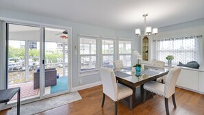 A dining area with a glass table, white cushioned chairs, and a chandelier. - 'the Waterfront Cottage' w/ Dock in Goodland! (Goodland)