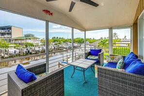 A covered outdoor seating area with wicker furniture and a view of a marina. - 'the Waterfront Cottage' w/ Dock in Goodland! (Goodland)