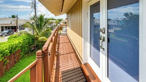 A balcony with a wooden railing, a door with a screen, and a view of a street with houses and cars. - 'the Waterfront Cottage' w/ Dock in Goodland! (Goodland)