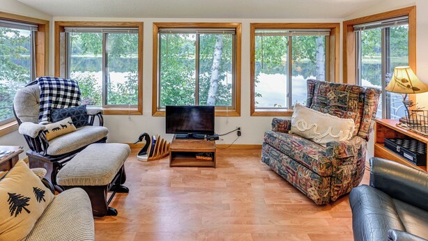 Una sala de estar con un ventanal, televisor y dos sillones estampados.