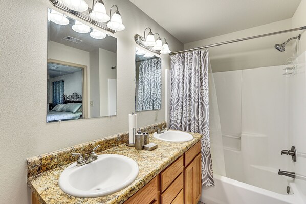 A bathroom with two sinks, a mirror, and a shower.