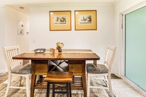 A dining area with a wooden table, four chairs, and two framed pictures on the wall. - Screened Porch: Family-friendly St Stephen Retreat (St. Stephen)