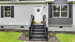 A two-story house with a front door, a staircase, and a small garden area. - Screened Porch: Family-friendly St Stephen Retreat (St. Stephen)