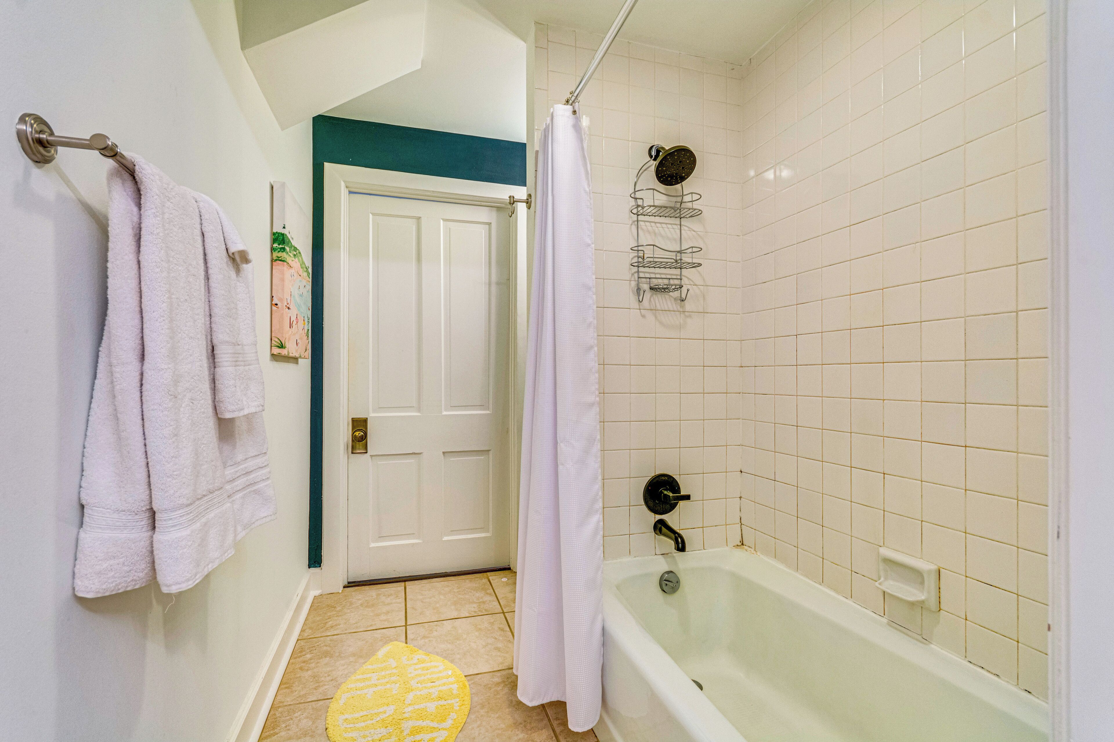 A bathroom with a bathtub, a shower, and a door leading to another room.