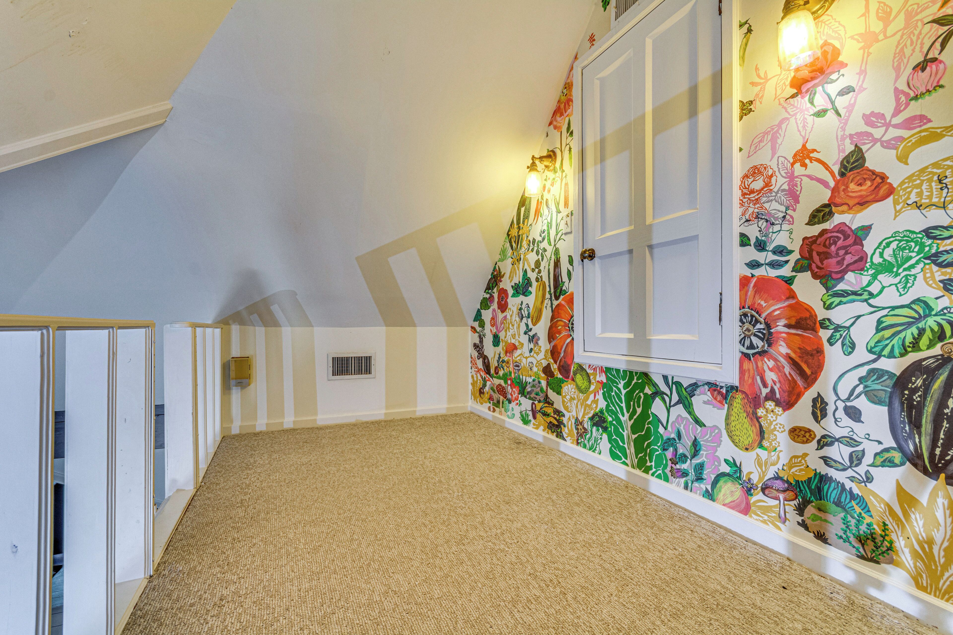 A hallway with a colorful floral wall mural, a carpeted floor, and a door with a white frame.