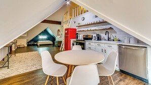 Une cuisine moderne de style industriel, avec un coin repas, un plancher en bois et une chambre à l’étage avec vue.