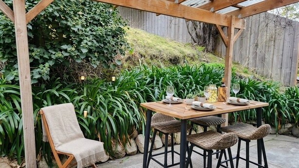 An outdoor patio with a wooden table and chairs, surrounded by lush greenery and a wooden fence. - Bowen Toft Villa- home-from-home (FIFO friendly) (Sandy Bay)
