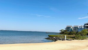 A beach with a clear sky, a sandy shore, and a row of buildings with a view of the water. - 5 Corner Store Ln Sunset Island | Resort Community (Ocean City)