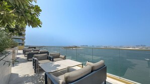 A rooftop terrace with outdoor seating and a view of the water. - Relaxing Beach Access 1 Bedroom in Grand Bleu (Dubai)