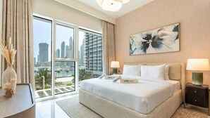 A hotel room with a large bed, two bedside tables, a city view, and a floral painting on the wall. - Relaxing Beach Access 1 Bedroom in Grand Bleu (Dubai)