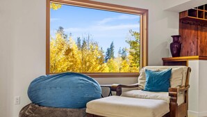 A room with a large window, a wooden chair with cushions, and a bean bag chair. - Back Road Bliss - Beautiful Frisco Home (Frisco)