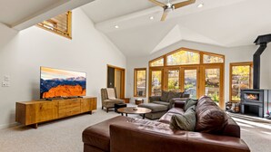 A spacious living room with a large leather sofa, a television, and a fireplace. - Back Road Bliss - Beautiful Frisco Home (Frisco)