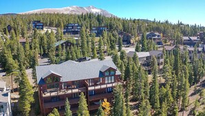 Un lodge a più piani con un tetto importante e numerosi balconi, circondato da una fitta foresta e una montagna sullo sfondo.