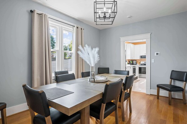A dining area with a wooden table, black chairs, and a vase with white feathers.