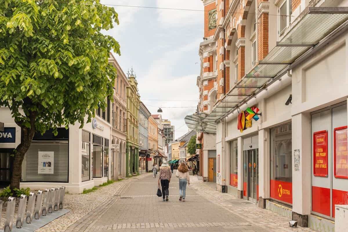 Une rue étroite bordée d’immeubles, dont certains abritent des boutiques et d’autres sont reconnaissables à leurs volets fermés.