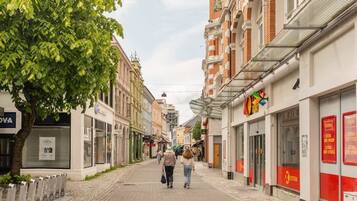 Une rue étroite bordée d’immeubles, dont certains abritent des boutiques et d’autres sont reconnaissables à leurs volets fermés.