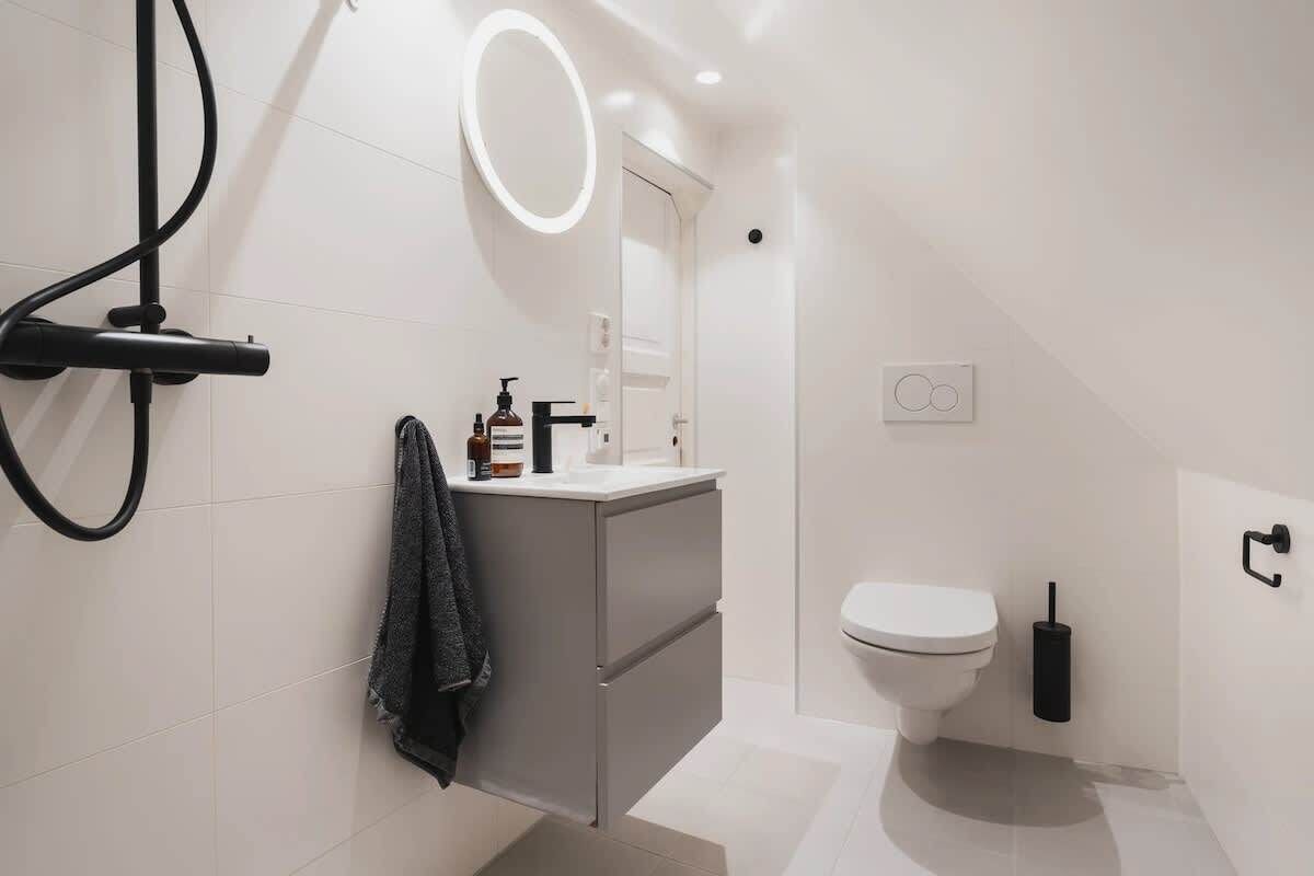 Casa de banho moderna com sanita, lavatório com espelho e porta-toalhas.
