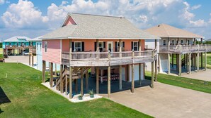 Une maison située en bord de mer, dotée d’une terrasse en bois et d’un patio couvert.