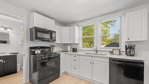 A modern kitchen with white cabinets, a black stove, and a dishwasher.