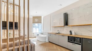Una cucina moderna con una vasca freestanding, una scala in legno e uno schienale in marmo.