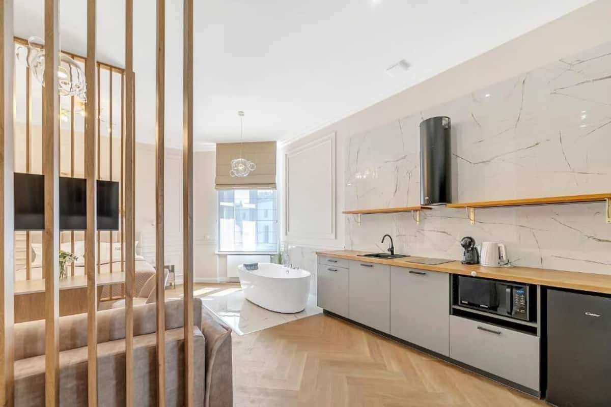 Una cocina moderna con una bañera independiente, una escalera de madera y un salpicadero de mármol.