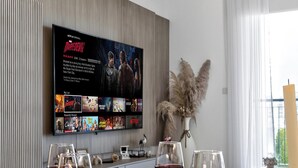 Un comedor moderno con un televisor de pantalla plana grande montado en la pared mostrando una película.