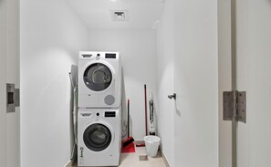 Un cuarto de lavandería con lavadoras apiladas y un trapeador.