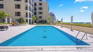 Una piscina profonda 1,2 metri, circondata da un edificio con balconi e posti a sedere all'aperto.