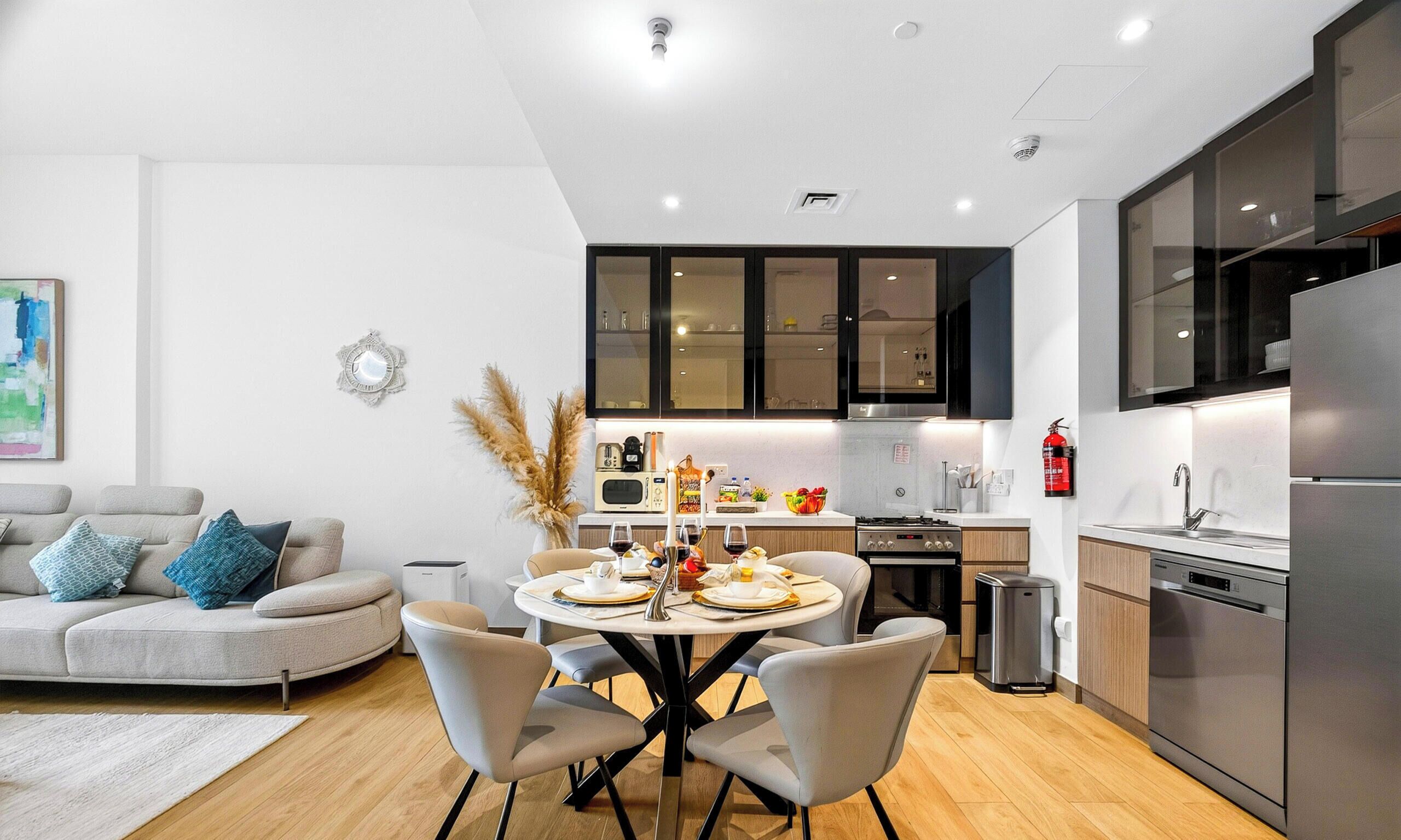 A modern kitchen with a dining area, a sofa, and a painting on the wall.