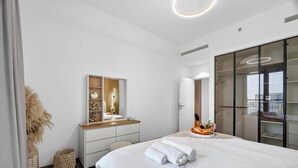 Un dormitorio moderno con cama, cómoda, espejo y armario.