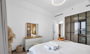 A modern bedroom with a bed, a dresser, a mirror, and a wardrobe. - WYZ RENT|Bayfront 1BR in La Sirene 2 Seaport View (Dubai)