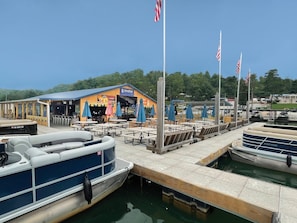 A marina with boats docked, a restaurant named 'SHARPER' with outdoor seating, and American flags.