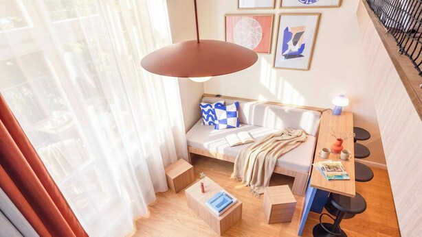 A modern living space with a sofa, a coffee table, a desk with chairs, and a hanging light fixture.