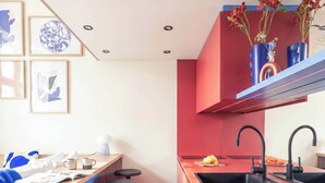 A modern kitchen with a red island, bar stools, and a sink with black faucets.