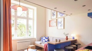 A modern kitchen with a bar area, a dining table, and a window with curtains.